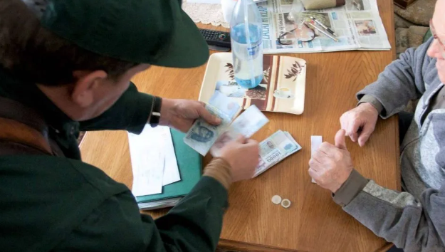 Postás számolja a pénzét egy asztalnál, a nyugdíjak emelésének szemléltetésére.